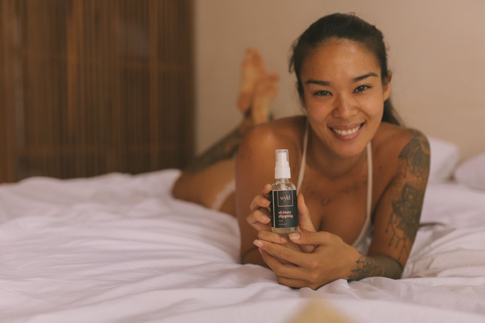 Woman smiling while holding a Wyld skincare bottle