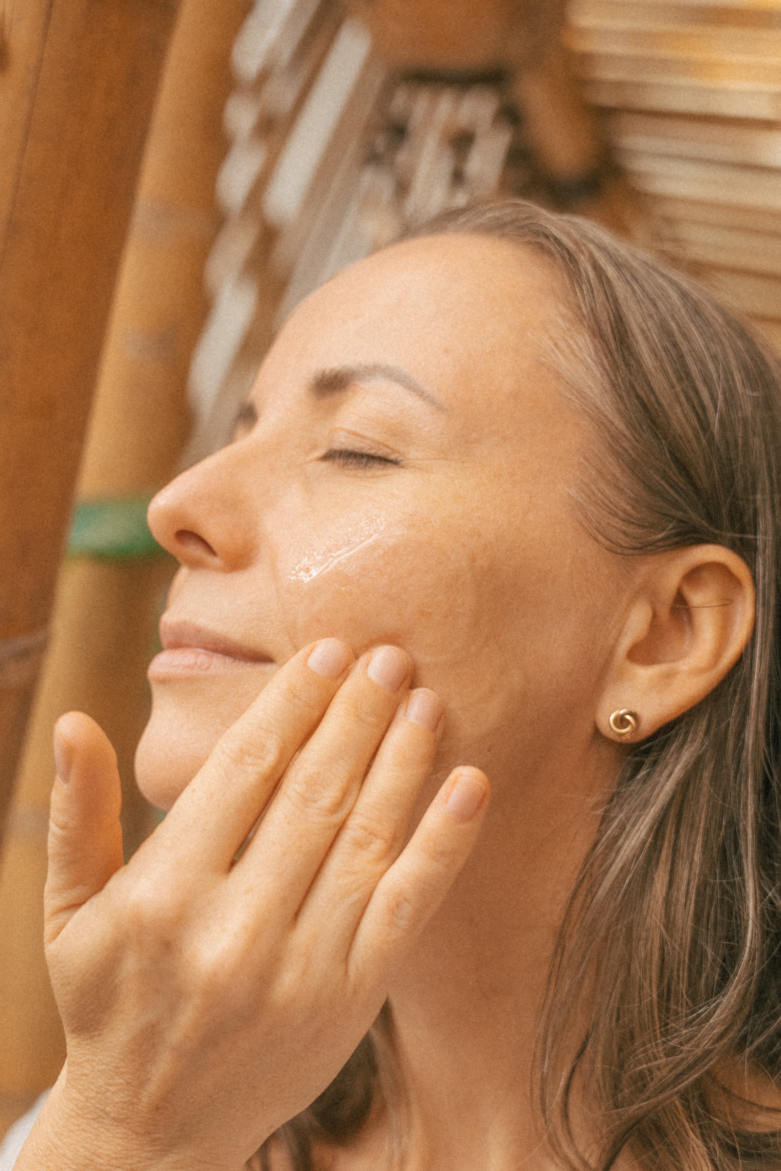 Woman applying serum with her eyes closed